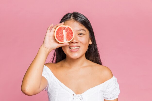 Foto gratuita donna che tiene un pompelmo e sorridere