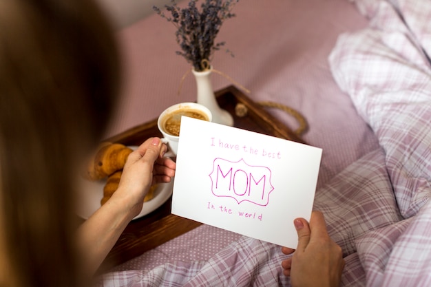 Woman holding greeting card and coffee cup on tray