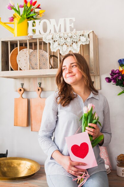 Woman holding greeting card and flowers