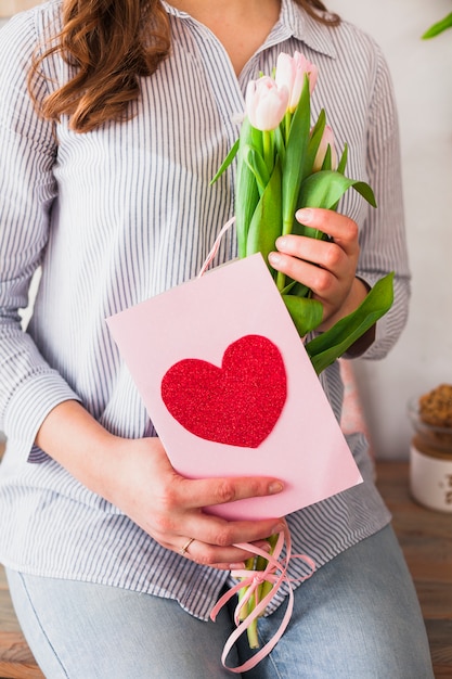 Woman holding greeting card and tulip flowers