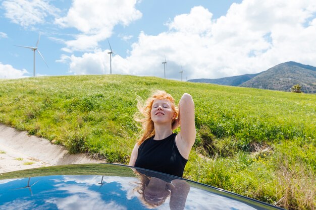 Woman holding hair and enjoying sun out of car window