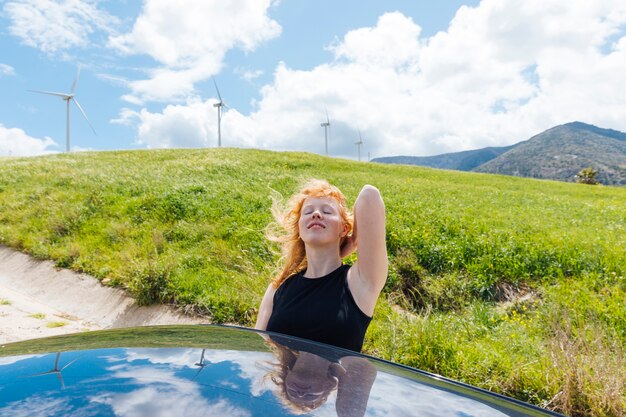 Женщина держит волосы и наслаждается солнцем из окна автомобиля