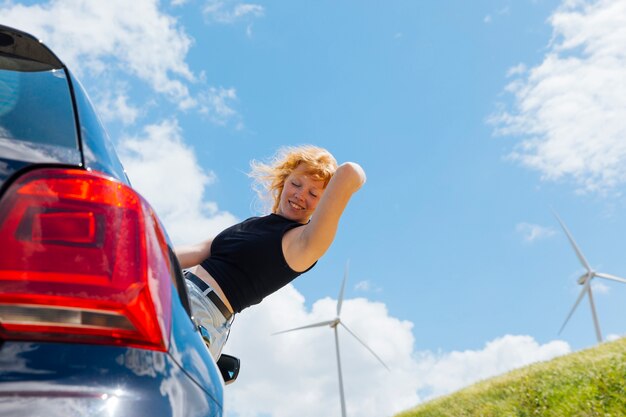 Woman holding hair and looking down out of car window