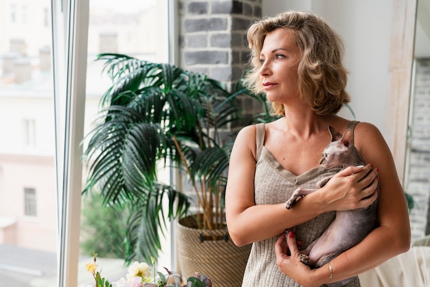 Woman holding hairless cat medium shot