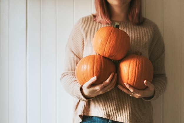 Foto gratuita donna che tiene le zucche di halloween in una fattoria