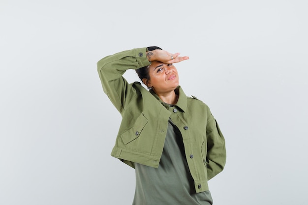 Free photo woman holding hand on forehead in jacket, t-shirt and looking cheery.