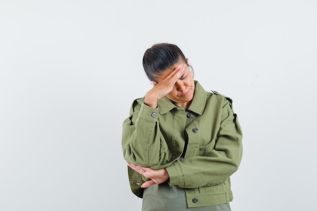 Woman holding hand over head in jacket, t-shirt and looking sorrowful