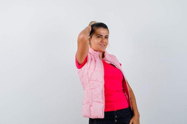 Woman holding hand on head in t-shirt, vest and looking relaxed 