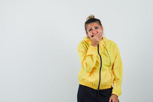 Free photo woman holding hand on mouth in sport suit and looking depressed , front view.