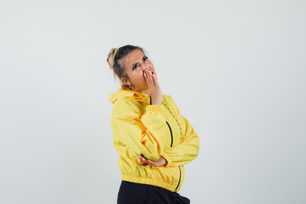 Woman holding hand near mouth in sport suit and looking pensive. front view.