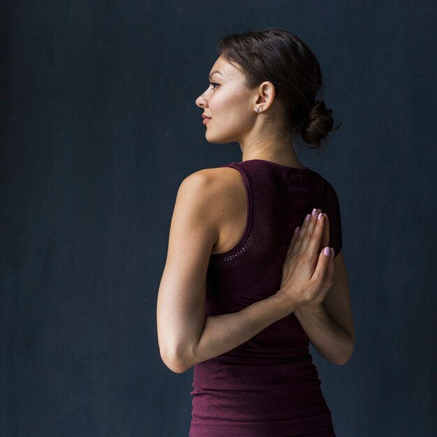 Woman holding hand in a praying pose behind her back