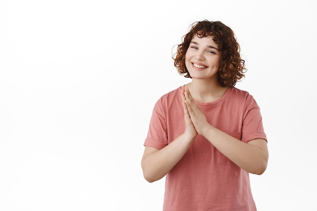 woman holding hands in pray namaste, press hands together politely, being grateful, thanking, standing in t-shirt on white.