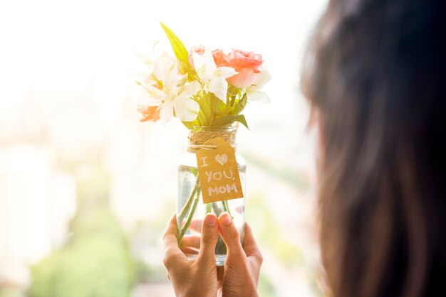 母の日の花の花瓶を手で保持している女性