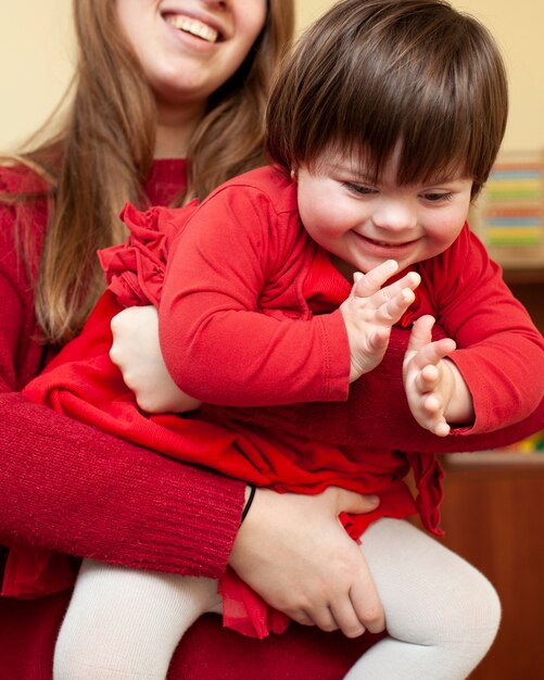 Woman holding happy child with down syndrome