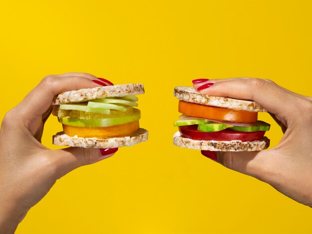 Woman holding healthy sandwiches on yellow background