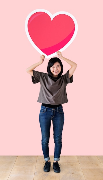 Woman holding a heart emoticon in a studio
