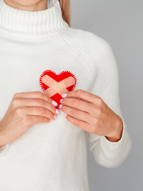 Free photo woman holding heart with band aids