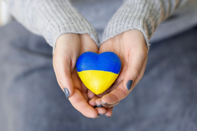 Free photo woman holding heart with ukrainian flag