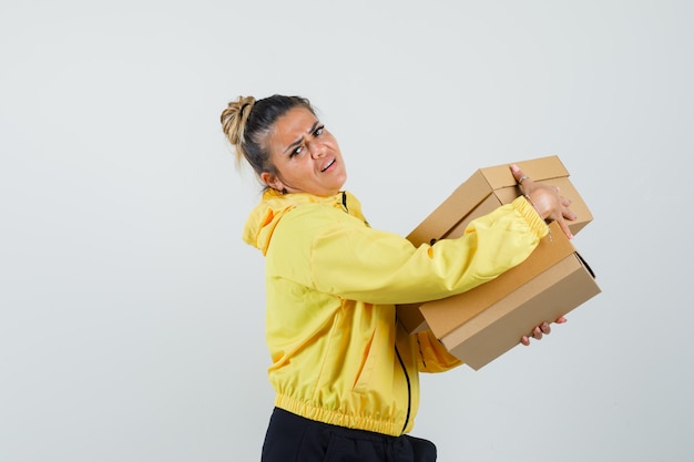 Woman holding heavy cardboard boxes in sport suit .