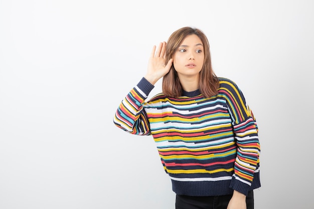 Free photo woman holding her hand near ear and listening carefully isolated on gray-white wall background.