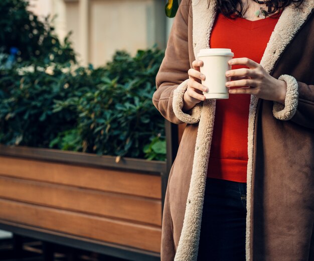 彼女の手で一杯のコーヒーを保持している女性