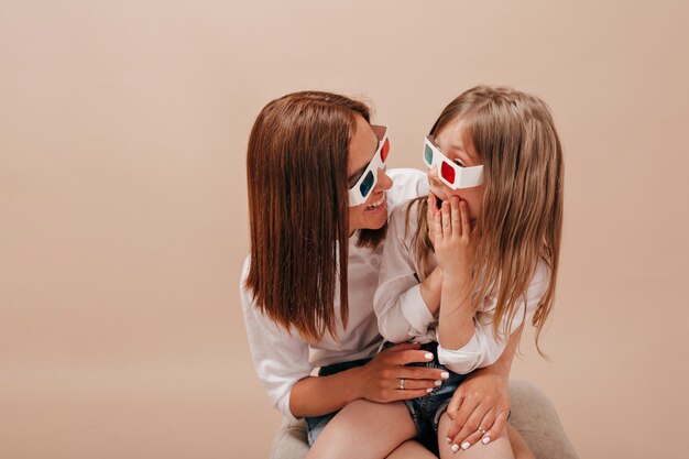 Woman holding her little charming girl and wearing glasses for cinema little girl watching movie with her mother