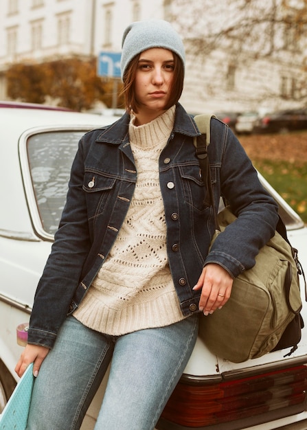 Donna che mantiene il suo skateboard mentre è seduto sulla macchina