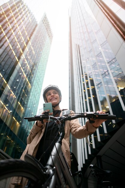 Женщина держит смартфон и идет на велосипеде