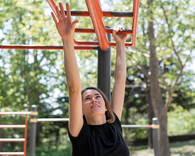 Woman holding herself by red metal bars