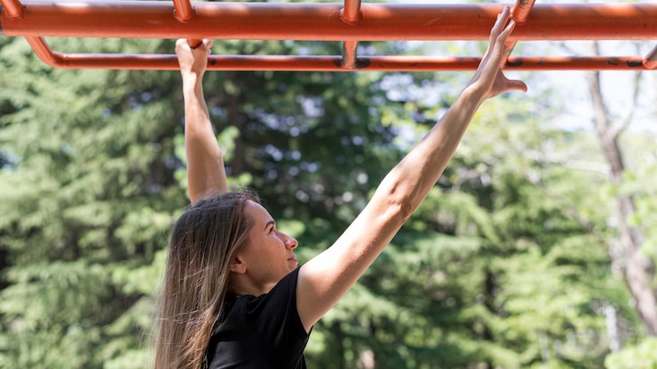 Free Photo woman holding herself up on a metal bar