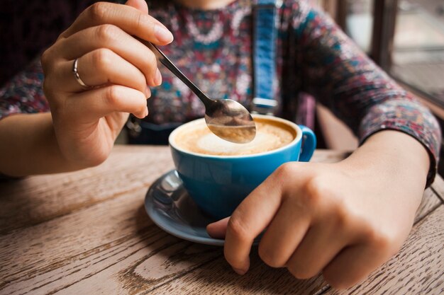 レストランで熱い一杯のコーヒーを保持している女性