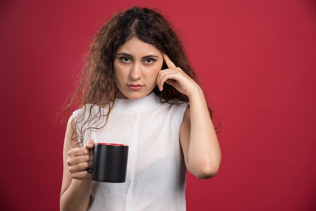 Free photo woman holding hot dark cup on red