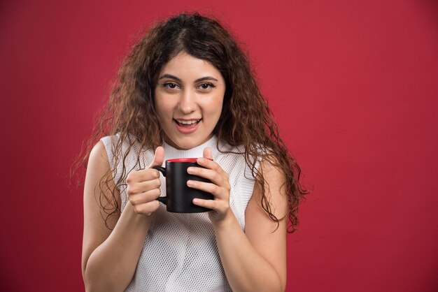 Woman holding hot dark cup on red