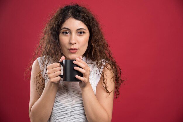 Woman holding hot dark cup on red