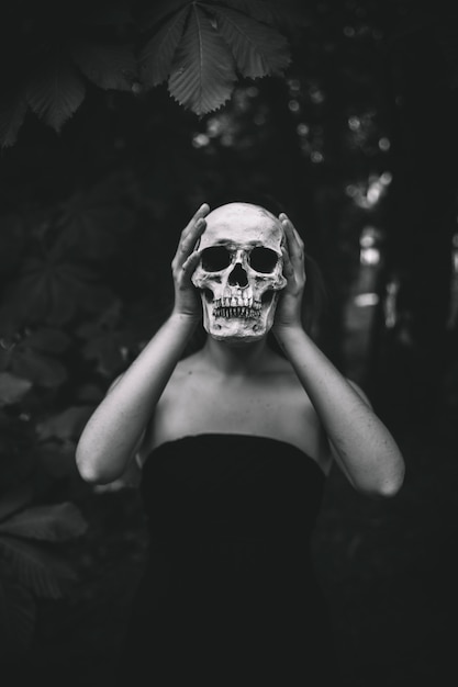 Free photo woman holding human skull in forest