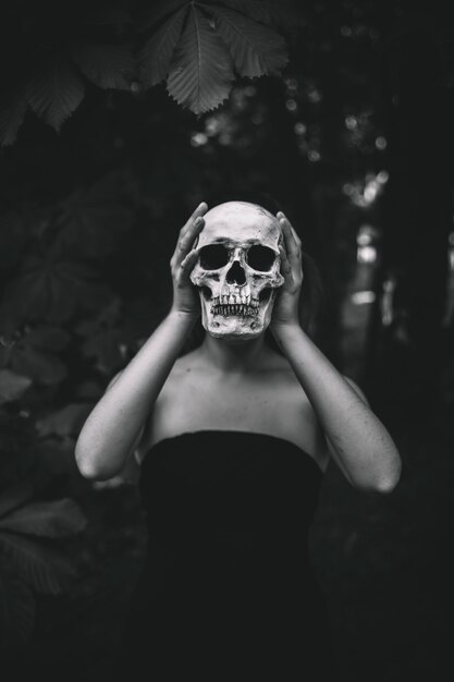 Woman holding human skull in forest