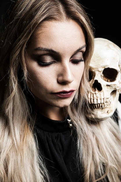 Free photo woman holding human skull on shoulder