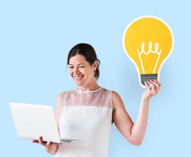 Woman holding an idea icon and using a laptop