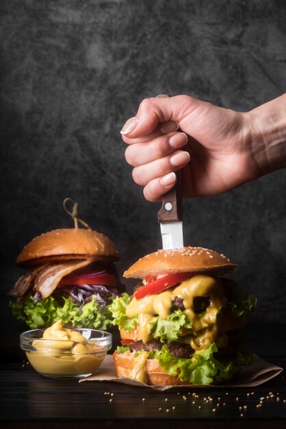 Женщина держит нож в вкусном гамбургере