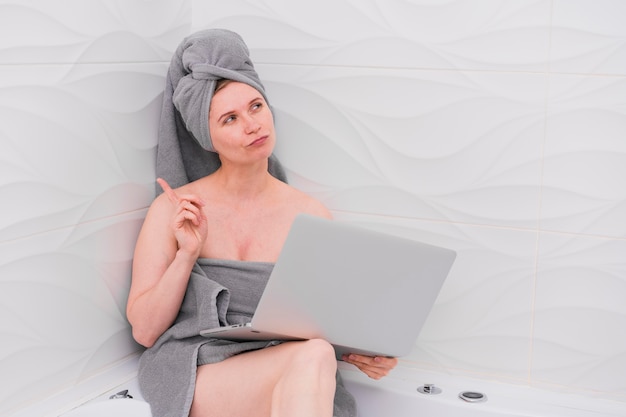 Foto gratuita donna che tiene un computer portatile nel bagno