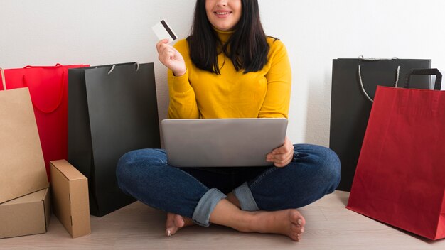 Woman holding a laptop on her lap next to shopping bags