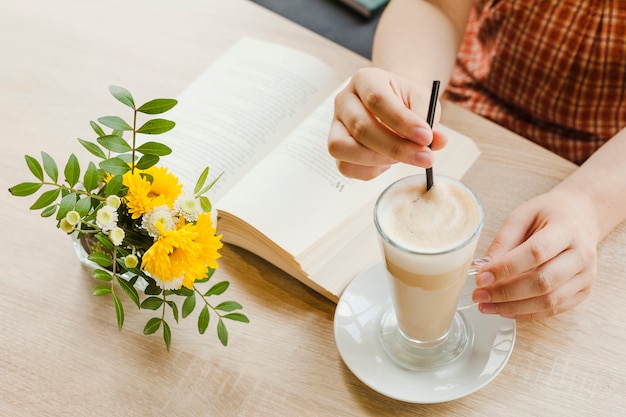 Женщина держит чашку латте, сидя в кафе