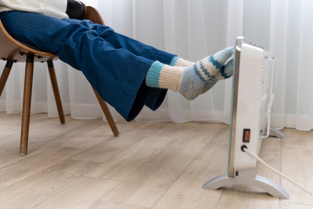 Woman holding legs on heater at home