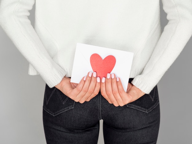 Free photo woman holding love envelope back view