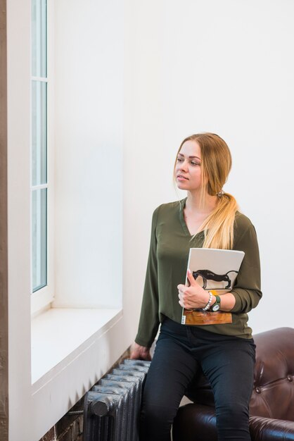 Woman holding magazine in her hand looking at window