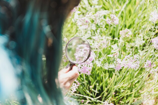 Woman holding magnifying glass over the flower