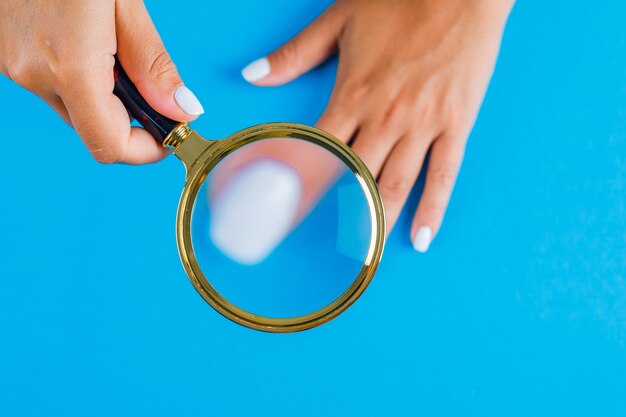 Woman holding magnifying glass over nail