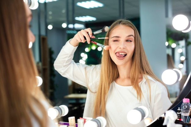Woman holding make-up brushes doing funny face