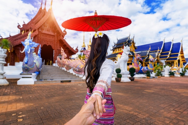 Woman holding man's hand and leading him to temple in Chiang Mai