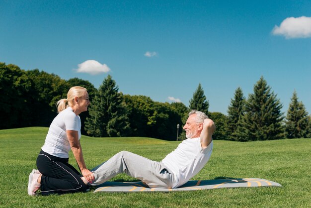 Woman holding man while he is doing crunches